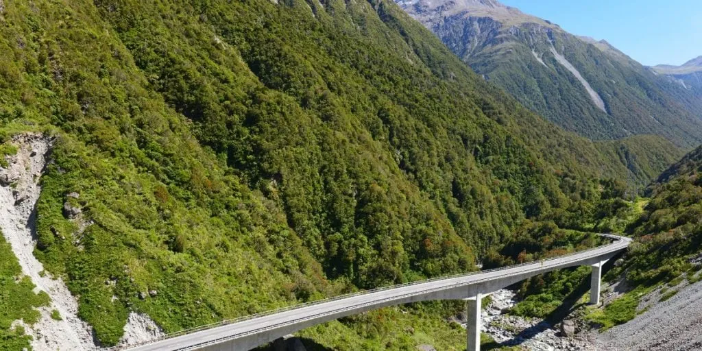 A highway viaduct curving through a steep, bush-covered alpine valley in Arthur's Pass