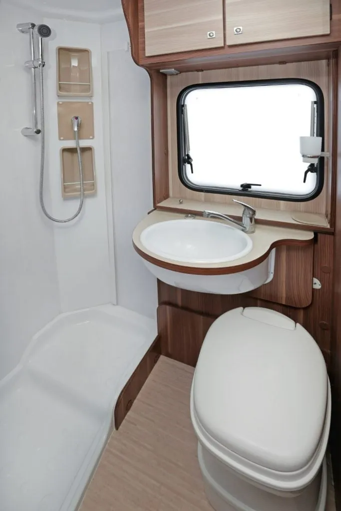 A compact motorhome bathroom with a moulded shower tray, hand basin and cassette toilet