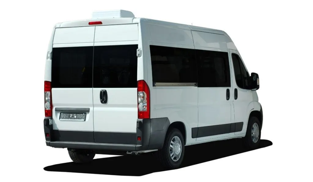 A white high-roof van campervan with windows along the side, seen from the rear three-quarter angle